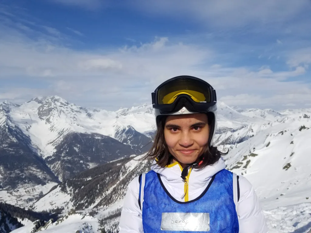Jugendliche mit Skibrille vor dem Bergpanorama.